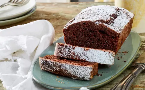 Saftiger Schokoladen-Pfundkuchen, bestäubt mit Puderzucker. Dieses Rezept für Pfundkuchen ist ein Genuss!