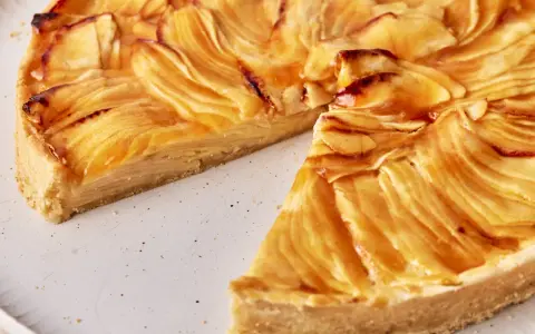 Eine köstliche Tarte au Pomme mit karamellisierten Apfelscheiben auf einem knusprigen Boden, auf einem rustikalen Teller.