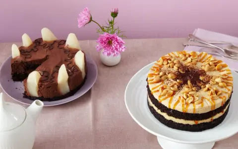 Zwei Torten auf einem Tisch: eine Schokoladen-Birnen-Torte und eine köstliche Erdnuss Torte mit Karamell und Nüssen.