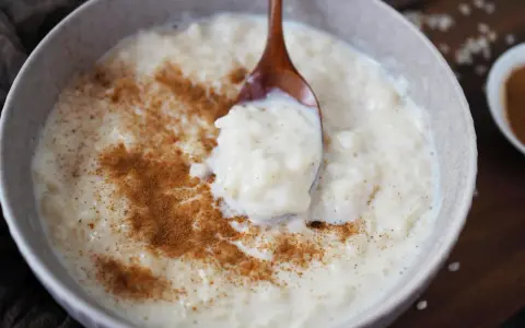 Cremiger Milchreis mit Zimt, der auf einem Holzlöffel serviert wird. Das Waschen des Milchreises ist ein wichtiger Schritt für die perfekte Konsistenz.