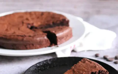 Ein Stück vom originalen Tarte au Chocolat Rezept, saftig und schokoladig, auf einem schwarzen Teller.