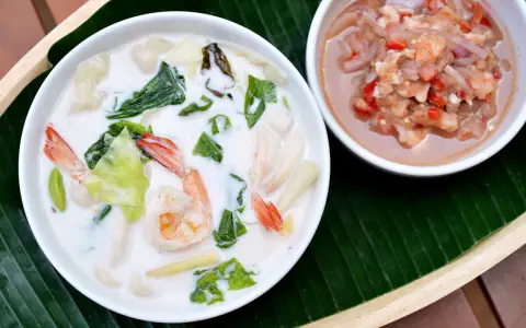 Eine cremige asiatische Suppe mit Garnelen und Gemüse, dane eine Schale mit einer würzigen Garnelenpaste.