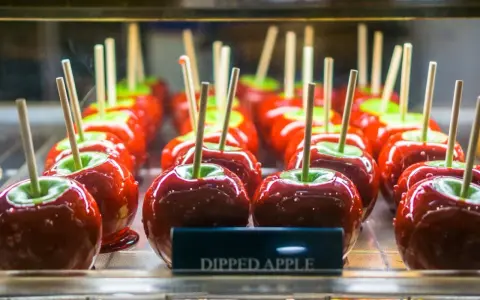 Glänzende, kandierte Fruchtschale Äpfel auf Spießen, bereit zum Genuss.