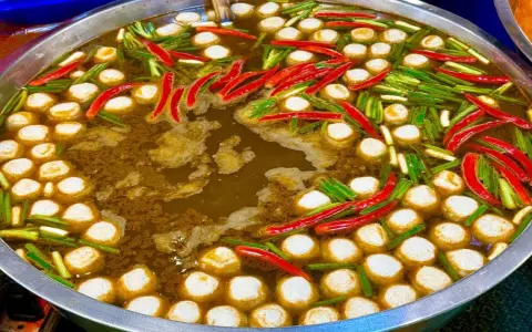Ein dampfender Topf mit Fleischbällchen, Chilis und Frühlingszwiebeln – ein Einblick in die vielfältigen Esskulturen weltweit.
