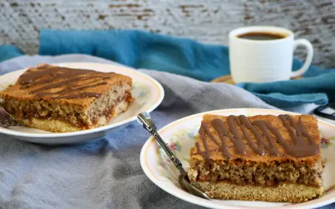 Zwei Stücke Blechkuchen mit Schokoladenglasur auf Tellern, perfekt, wenn man den Blechkuchen 3 Tage vorher backen möchte. Dazu eine Tasse Kaffee.