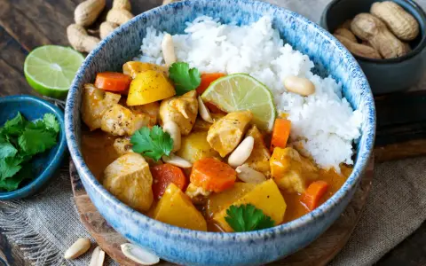 Ein köstlicher Massaman Curry mit Hühnchen, Kartoffeln, Karotten und Erdnüssen, serviert mit Reis. Der Massaman Curry Geschmack ist intensiv und aromatisch.