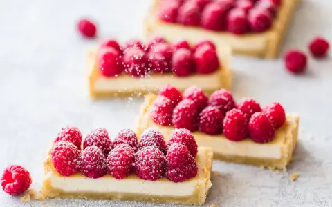 Drei rechteckige Tarte aux fruits mit frischen Himbeeren und Puderzucker bestreut.