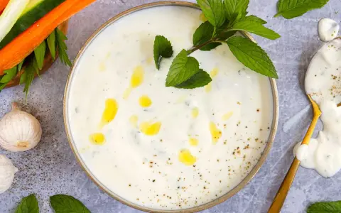 Cremiger Joghurt-Dip mit Minze und Knoblauch, perfekt für ein leichtes minzjoghurt rezept. Dazu Gemüsesticks.