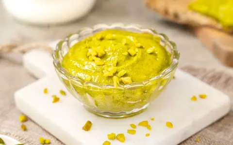 Selbstgemachtes Pistazienmus in einer Glasschale, garniert mit gehackten Pistazien. Perfekt zum Brot oder als Dip.