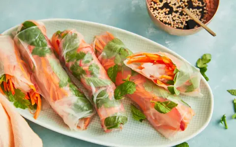Frische Sommerrollen mit knackigem Gemüse und Garnelen, perfekt für ein leichtes Sommerrollen Rezept original. Dazu eine Dip-Schale mit Sesam.
