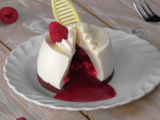Ausgefallene Desserts zum Vorbereiten: Ein cremiges Dessert mit Himbeersauce und frischer Himbeere, dekoriert mit einem gelben Schokoladen-Detail.