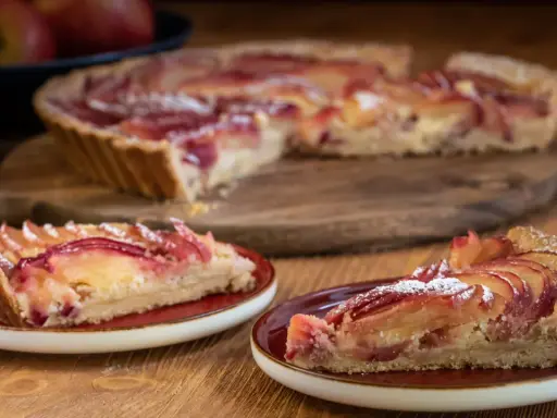 Saftige Apfeltarte mit roten Apfelscheiben, bestäubt mit Puderzucker. Ein köstliches Apfeltarte Rezept für Genießer.