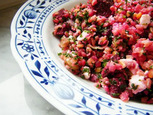 Bunter rote Bete Salat mit Linsen und Feta, garniert mit frischer Petersilie, serviert auf einem Teller mit blauem Blumenmuster.