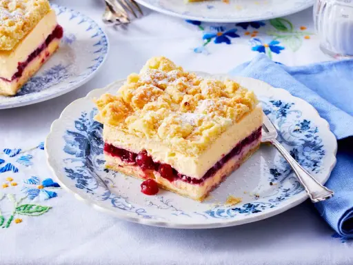 Ein Stück bester Pudding-Kuchen mit Kirschen und Streuseln auf einem blumengemusterten Teller.