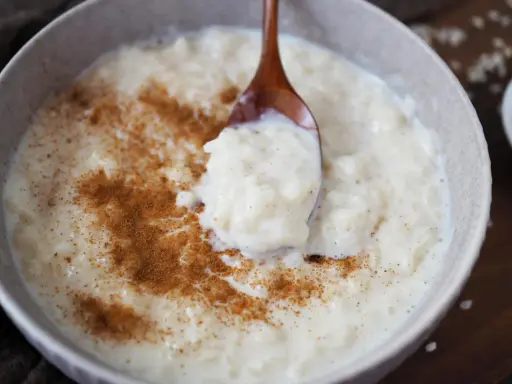 Cremiger Milchreis mit Zimt, der auf einem Holzlöffel serviert wird. Das Waschen des Milchreises ist ein wichtiger Schritt für die perfekte Konsistenz.