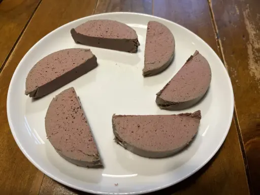 Sechs Scheiben Pastete auf einem weißen Teller, bereit zum Servieren. Ein köstliches pâté rezept, das man probieren muss!