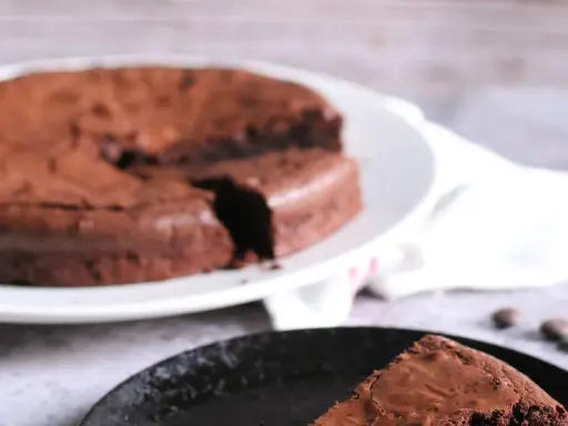 Ein Stück vom originalen Tarte au Chocolat Rezept, saftig und schokoladig, auf einem schwarzen Teller.