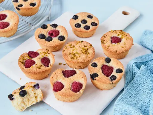 Kleine, goldbraune Financiers mit Himbeeren, Blaubeeren und Pistazien. Ein köstliches Financier Rezept zum Nachbacken.
