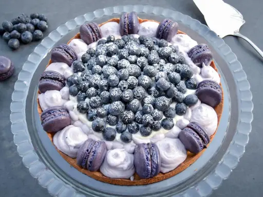 Eine Macaron Torte mit Blaubeeren und lila Macarons, bestäubt mit Puderzucker.