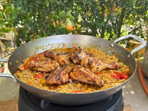Eine köstliche Paella mit Hähnchenstücken und Paprika, die zeigt, was ist paella: ein herzhaftes Reisgericht.