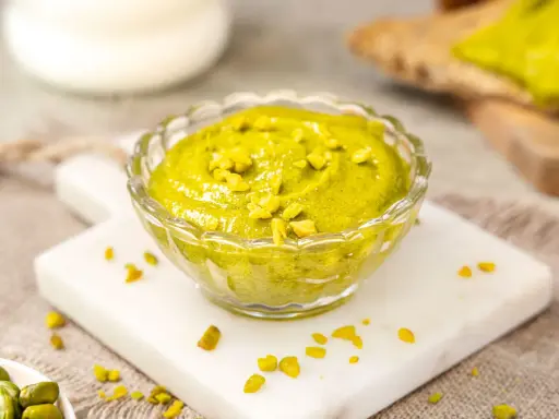 Selbstgemachtes Pistazienmus in einer Glasschale, garniert mit gehackten Pistazien. Perfekt zum Brot oder als Dip.