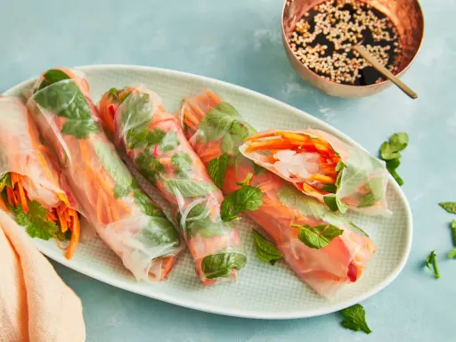 Frische Sommerrollen mit knackigem Gemüse und Garnelen, perfekt für ein leichtes Sommerrollen Rezept original. Dazu eine Dip-Schale mit Sesam.