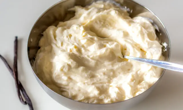 Schüssel mit cremiger, italienischer Vanillecreme, daneben zwei Vanilleschoten.