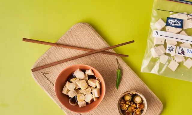 Vorbereitung für tofu einfrieren: gewürfelter Tofu in Schüssel mit Soße, Stäbchen, Chili und Beutel mit gefrorenem Tofu.