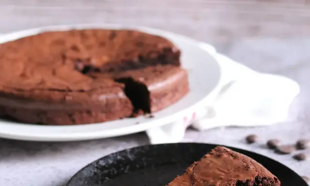 Ein Stück vom originalen Tarte au Chocolat Rezept, saftig und schokoladig, auf einem schwarzen Teller.