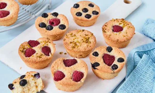 Kleine, goldbraune Financiers mit Himbeeren, Blaubeeren und Pistazien. Ein köstliches Financier Rezept zum Nachbacken.
