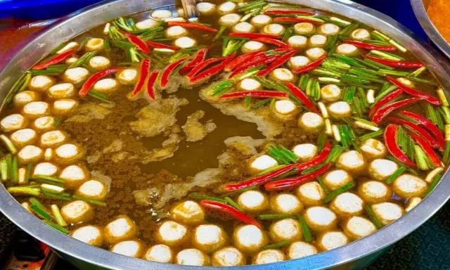 Ein dampfender Topf mit Fleischbällchen, Chilis und Frühlingszwiebeln – ein Einblick in die vielfältigen Esskulturen weltweit.