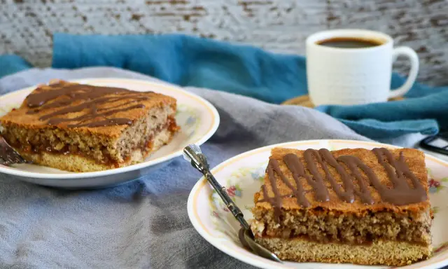 Zwei Stücke Blechkuchen mit Schokoladenglasur auf Tellern, perfekt, wenn man den Blechkuchen 3 Tage vorher backen möchte. Dazu eine Tasse Kaffee.