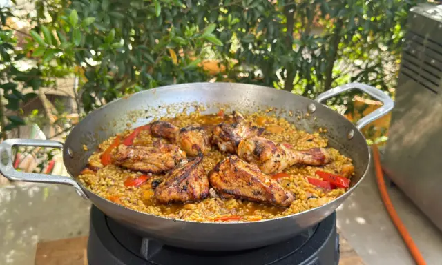 Eine köstliche Paella mit Hähnchenstücken und Paprika, die zeigt, was ist paella: ein herzhaftes Reisgericht.