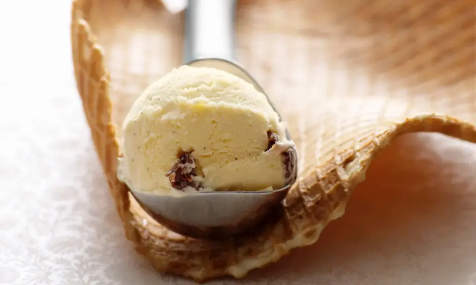 Ein Löffel cremiges Malaga Eis mit Rosinen, bereit für ein Waffelhörnchen. Ein einfaches Malaga Eis Rezept für den Sommer.