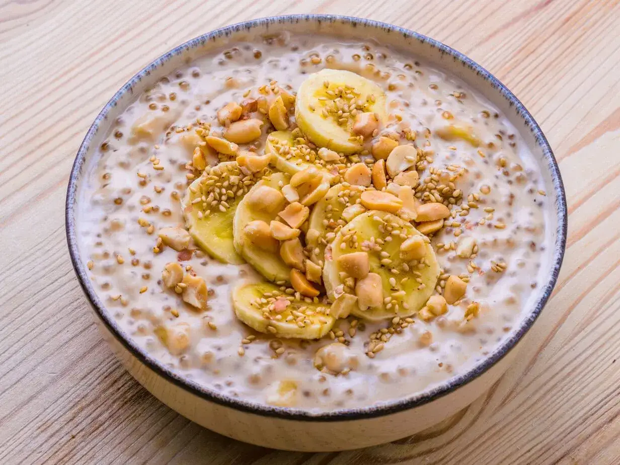 Sch&uuml;ssel mit vietnamesischem Dessert: cremiger Tapiokapudding mit Bananenscheiben, Erdn&uuml;ssen und Sesam.