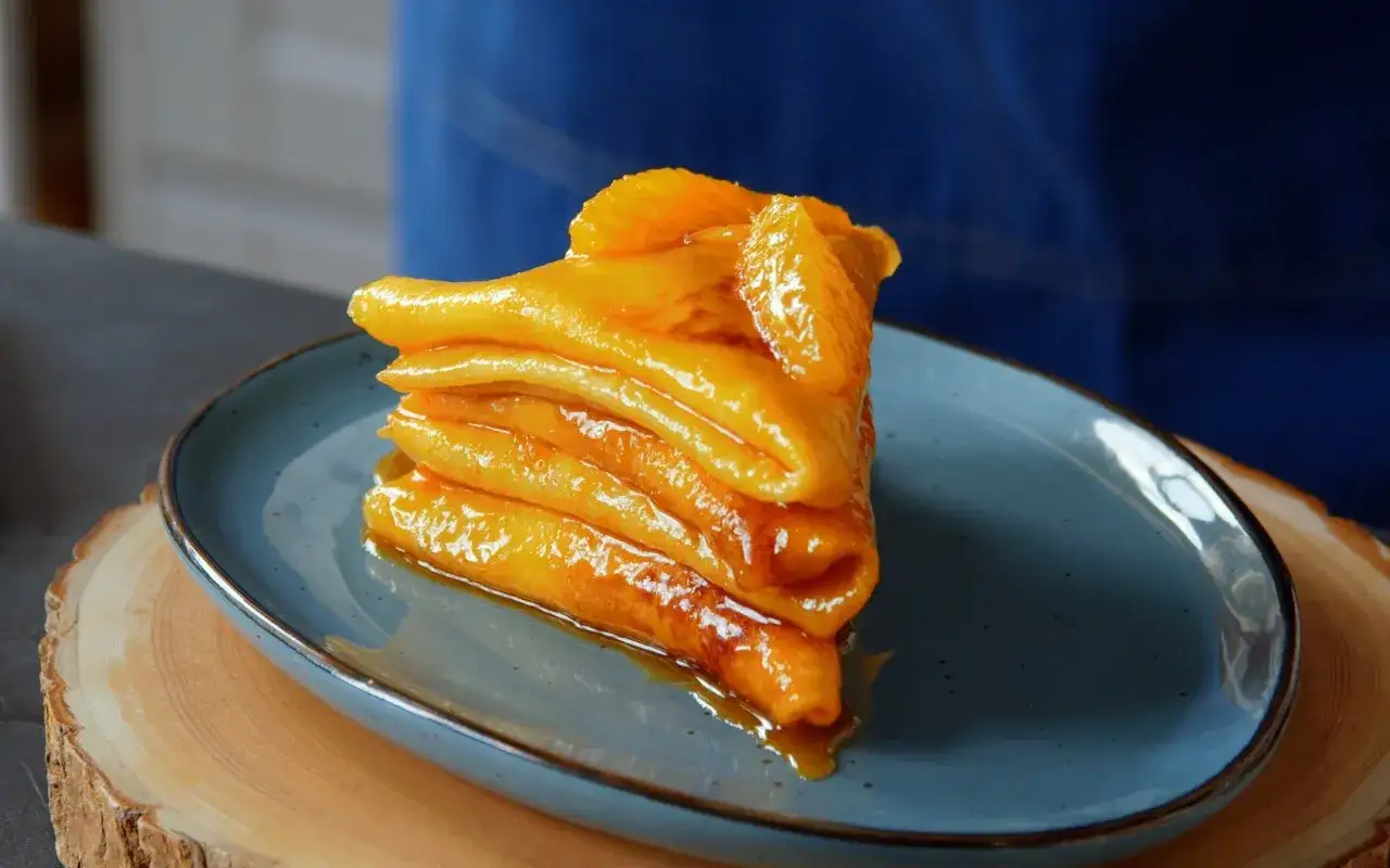 Gestapelte Cr&ecirc;pes Suzette, glasiert und mit Orangenspalten garniert, ein wahrer Genuss nach dem originalen Cr&ecirc;pe Suzette Rezept.