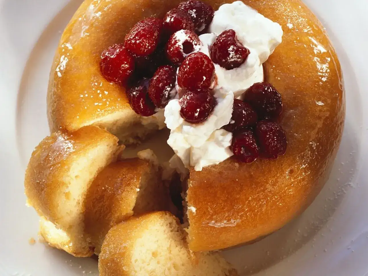 Ein goldbrauner Savarin mit Sahne und roten Beeren, ein köstliches Savarin Rezept.