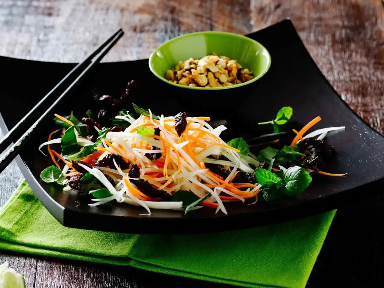 Ein bunter Papaya Salat vietnamesisch mit Karottenstreifen, Kr&auml;utern und ger&ouml;steten Erdn&uuml;ssen.