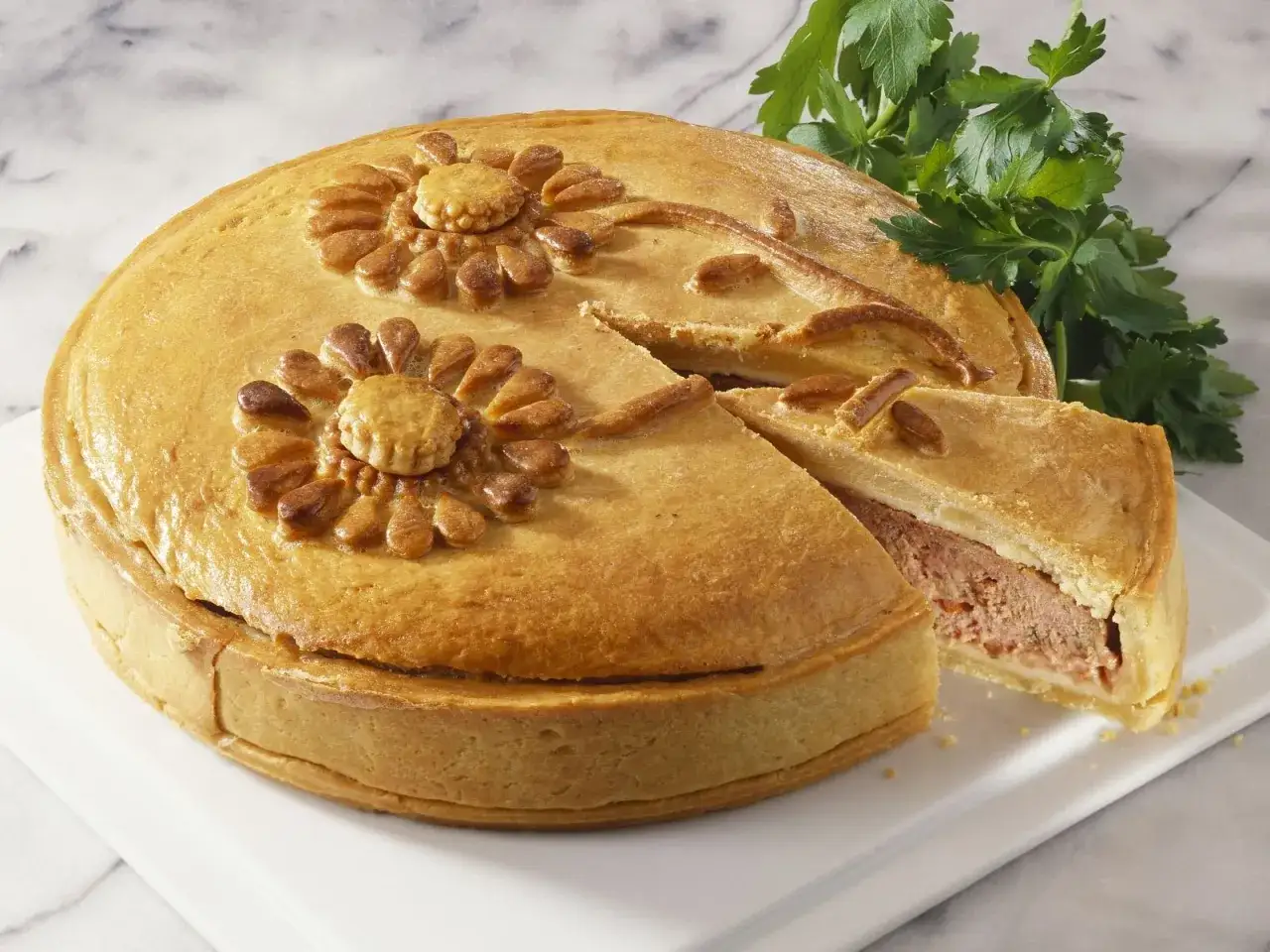 Goldbraune Pastete mit Blumenmuster, ein St&uuml;ck herausgeschnitten. Ein k&ouml;stliches pastete rezept f&uuml;r jeden Anlass.