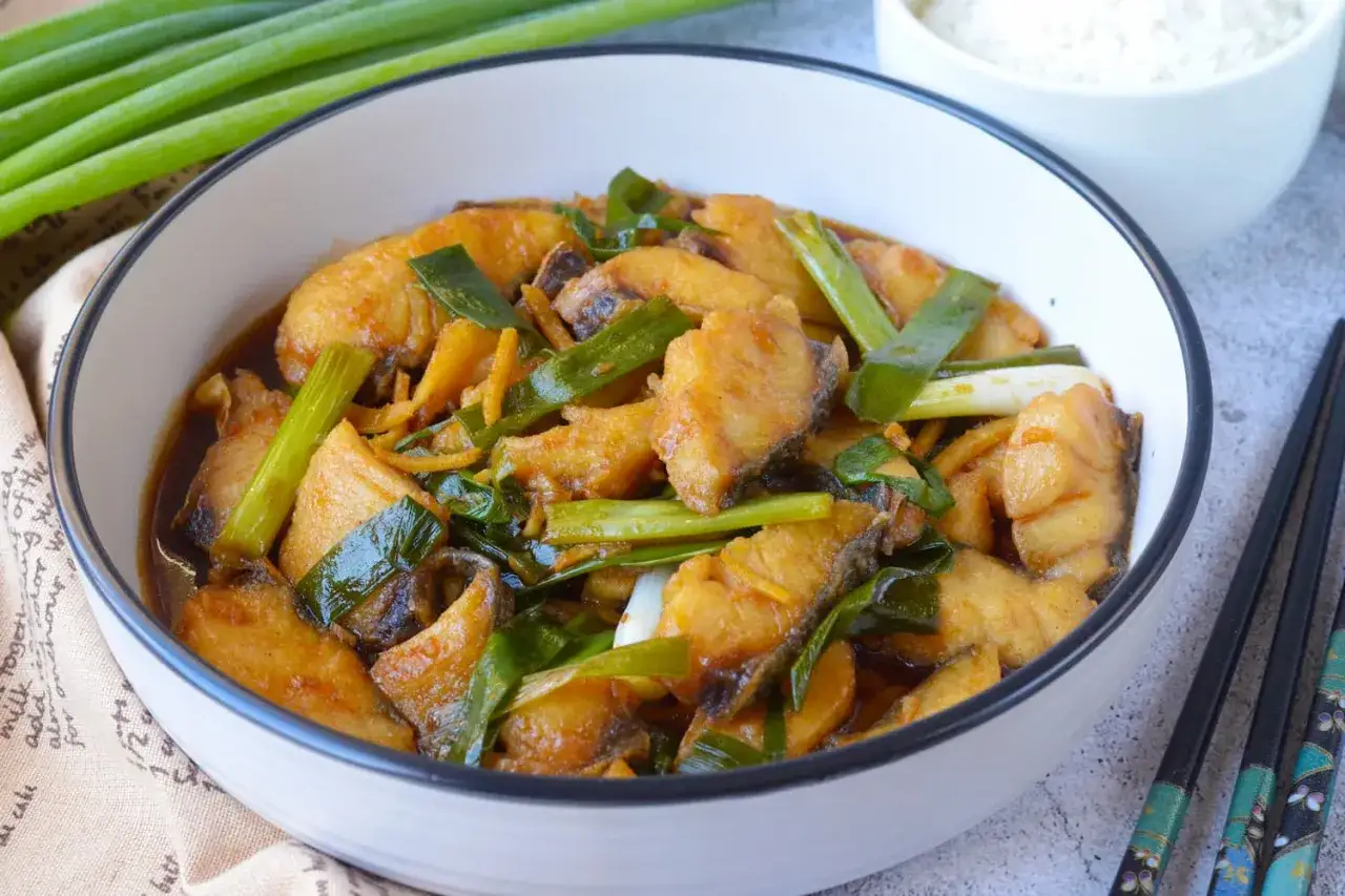 Ein k&ouml;stlicher, asiatischer Fisch in einer dunklen Sauce mit Fr&uuml;hlingszwiebeln und Ingwer.