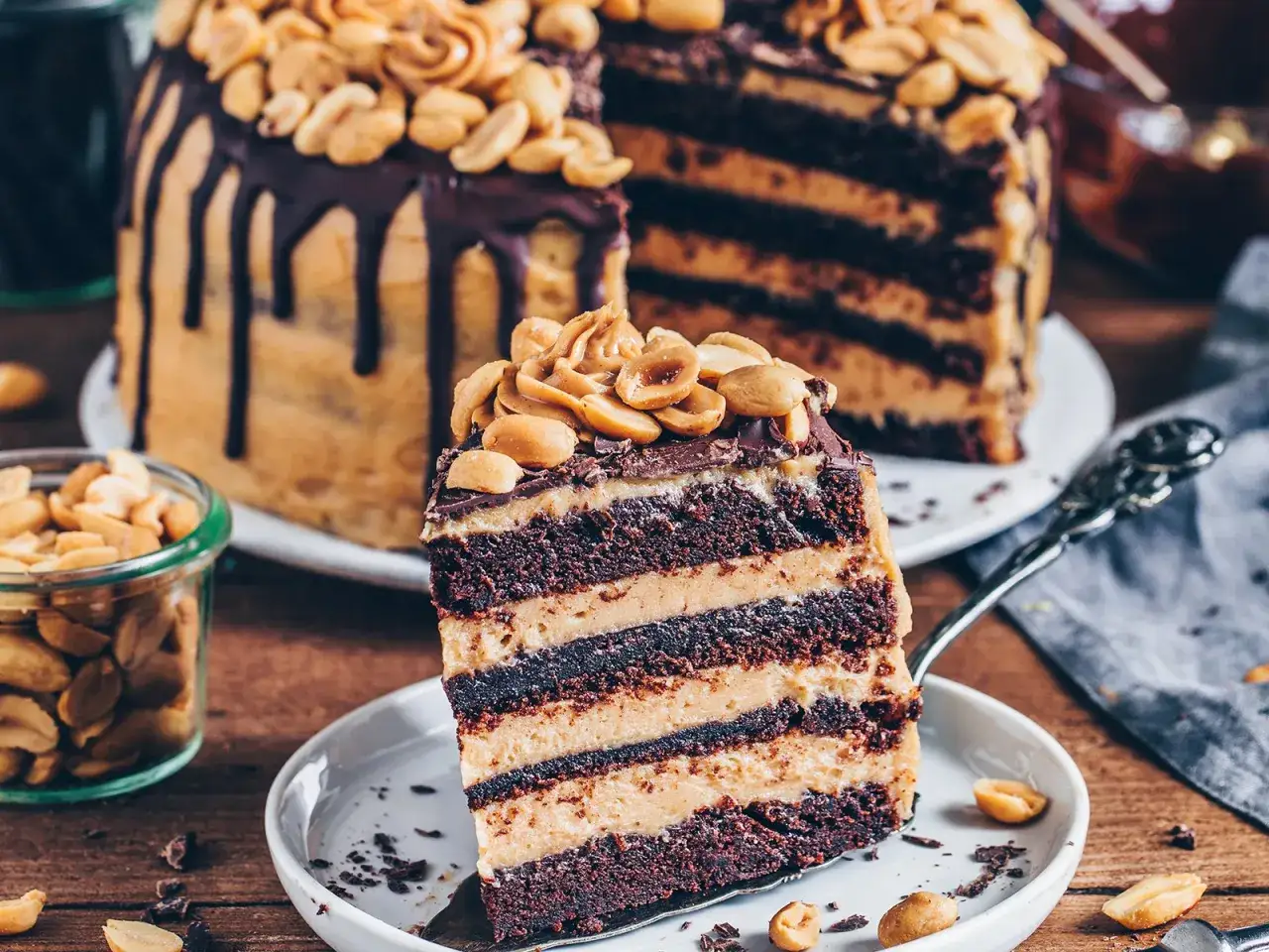 Ein St&uuml;ck saftige Schokoladen-Erdnuss-Torte mit vielen Schichten und Erdn&uuml;ssen obendrauf.