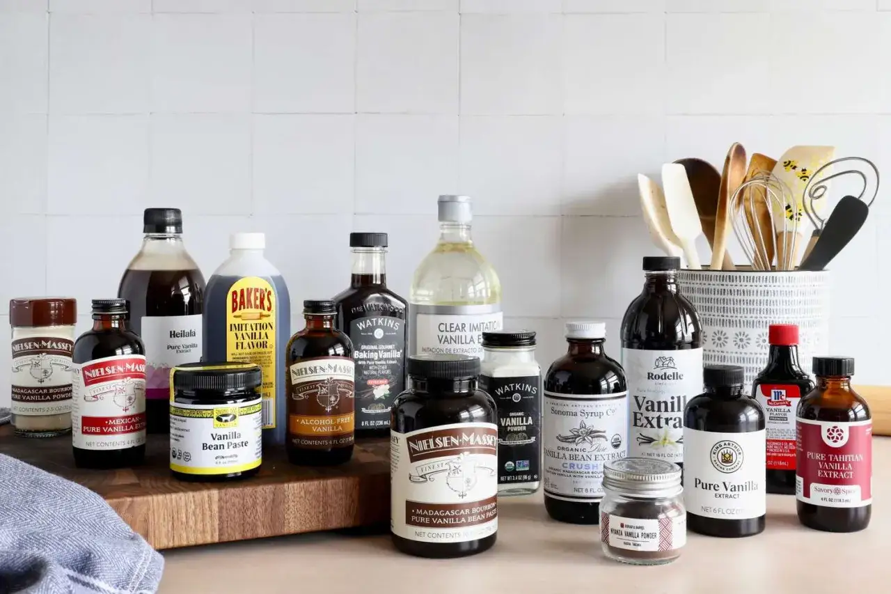Vielfalt an Vanilleprodukten: Extrakte, Pasten und Pulver als vanilleschote alternative. Backutensilien im Hintergrund.