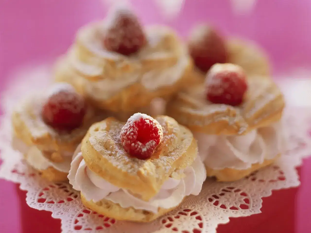 Windbeutel mit Himbeeren und Sahne, ein s&uuml;&szlig;es Dessert, best&auml;ubt mit Puderzucker.