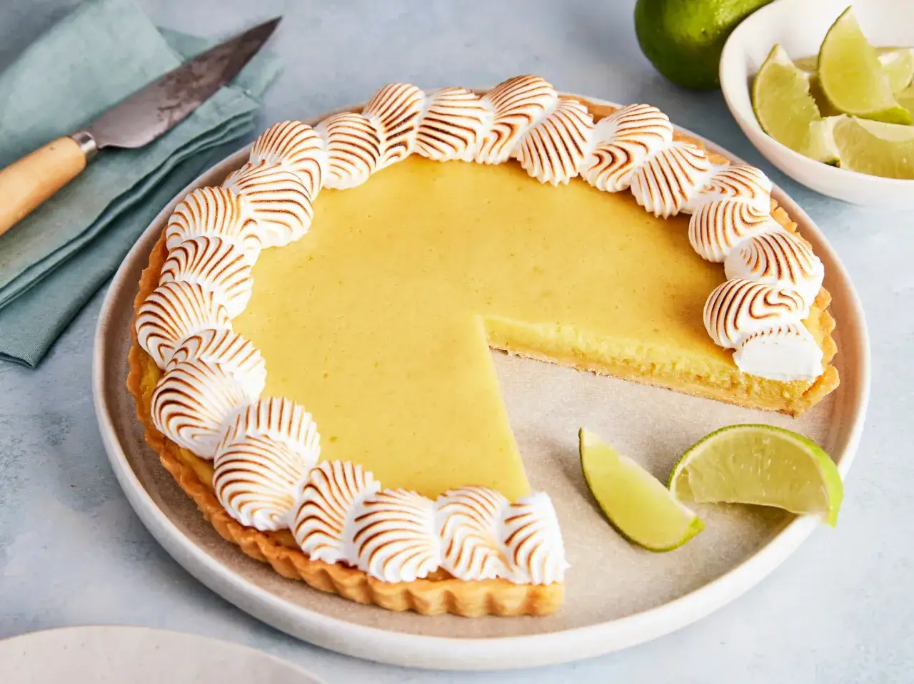 Eine k&ouml;stliche Limetten Tarte mit gebackener Baiserhaube, garniert mit frischen Limettenspalten.