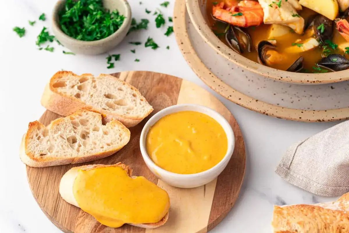 Ein k&ouml;stliches Rouille-Rezept: Brot mit cremiger Sauce, garniert mit Petersilie. Dazu eine Bouillabaisse mit Garnelen und Muscheln.