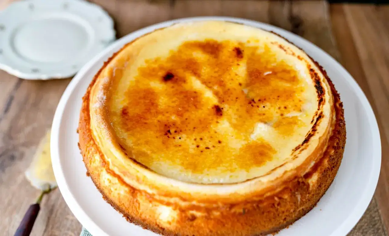 Ein k&ouml;stlicher Creme Brulee Kuchen mit karamellisierter Zuckerkruste auf einer wei&szlig;en Platte.