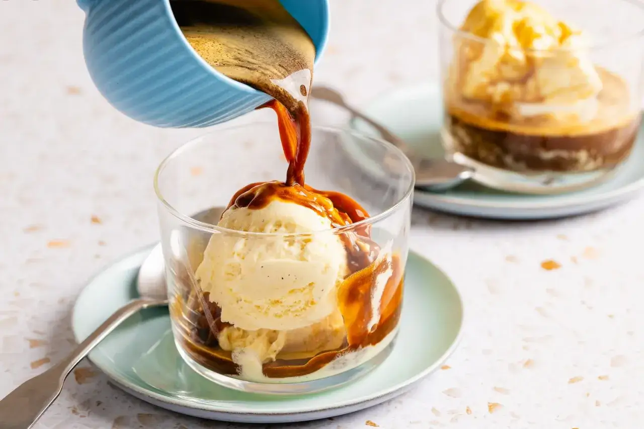Hei&szlig;er Espresso flie&szlig;t &uuml;ber cremige italienische Vanillecreme in einem Glas. Ein k&ouml;stlicher Affogato-Moment.