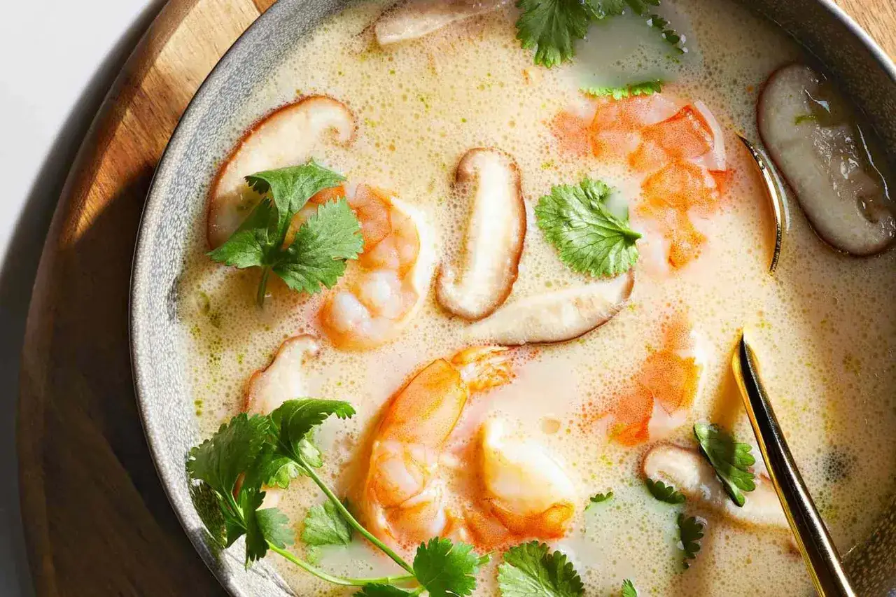 Eine cremige garnelensuppe asiatisch mit Shiitake-Pilzen und frischem Koriander, serviert in einer grauen Sch&uuml;ssel.