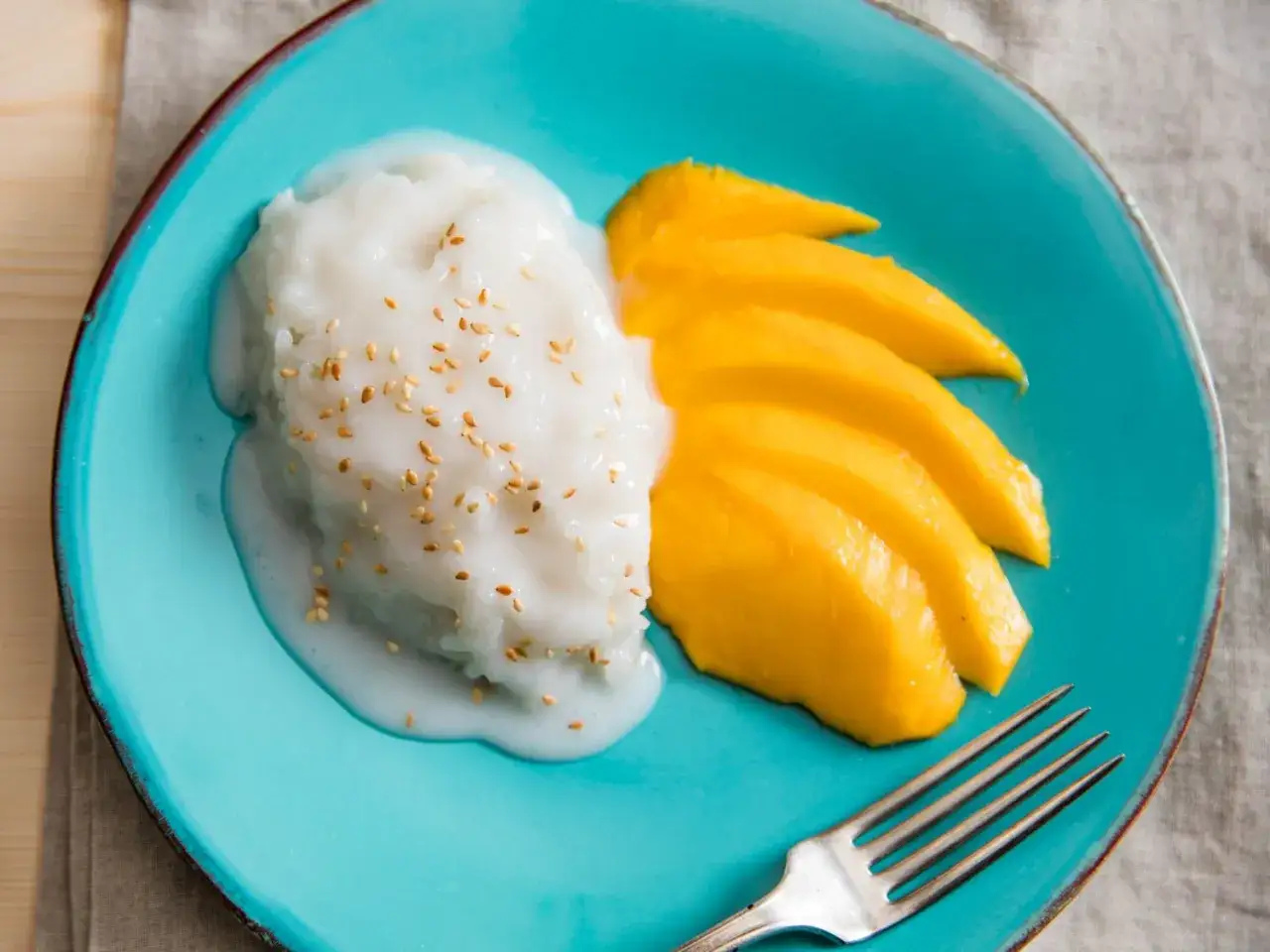 Ein köstlicher thailändischer Mango-Dessert mit Klebreis, Kokosmilch und Sesam.