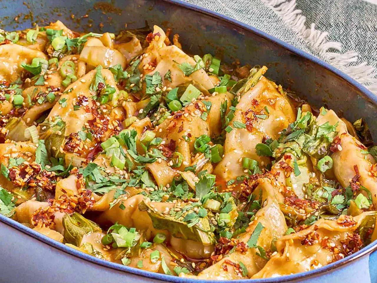 Herzhafte Teigtaschen in w&uuml;rziger Sauce, garniert mit Fr&uuml;hlingszwiebeln und Chili. Ein k&ouml;stliches Beispiel f&uuml;r asiatische Rezepte.